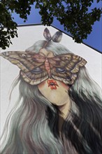 Portrait of a woman with pointed lips and butterfly in front of her face