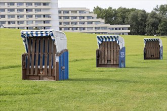 Row of blue beach chairs on a green meadow with dyke on the beach of Cuxhaven