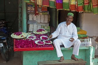 Vendor in front of shop selling scarfs and flowers as gifts for offerings near the Nizam-Ud-Din shrine in Delhi