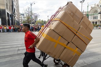 Man pulling cart loaded with large cardboard boxes