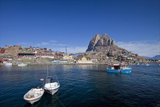 Uummannaq village with colourful houses and fishing boats in front of Heart Mountain