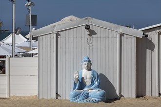 Buddha figure in front of a white beach hut