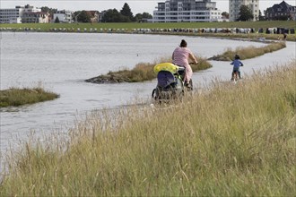 Cyclist on flooded shore path at high tide on the beach of Cuxhaven