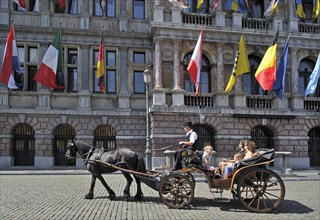 Horse and carriage with tour guide and tourists during sightseeing trip in front of city Hall at the Grote Markt