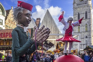 Puppeteer and street performer performing balancing act on giant ball during Christmas market in winter in Ghent
