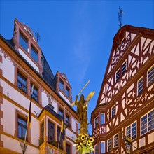 St. Michael's Fountain with town hall and gabled half-timbered house in the evening