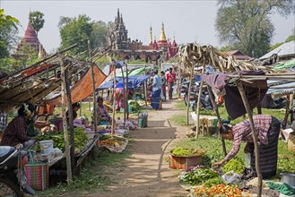 Burmese women selling vegetables at food market in front of Buddhist temples in Myanmar
