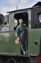 Engine driver driving steam train at the depot of the Chemin de Fer a Vapeur des Trois Vallees at Mariembourg