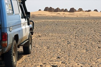 Four-wheel drive vehicle approaching the pyramids of Meroe in the Sudanese desert