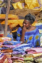 Black woman in traditional clothing selling colourful cloths on market in Nouakchott