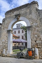 Touring bicycle in front of remains of ancient Roman city gate in the town Pore?