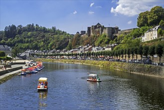 Paddle boats with tourists on the Semois river in front of Chateau de Bouillon Castle in summer