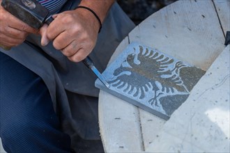 Albanian sculptor chopping making the country's coat of arms in the stone