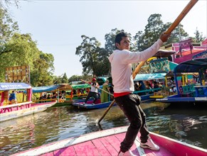 Popular tourist attraction people boating on colourful barges on canal at Xochimiloco