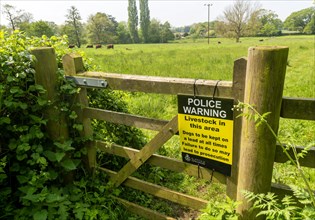 Police warning sign on gate about livestock in field