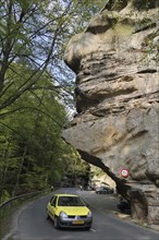 Car driving under the sandstone rock formation Predigtstuhl in Berdorf