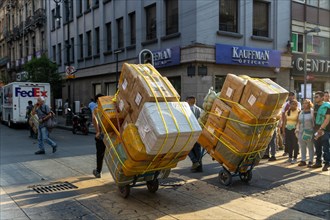 Men pulling carts loaded with large cardboard boxes