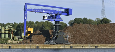 Dock crane and scrap heap along the Ghent-Terneuzen Canal at Ghent seaport
