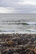 Stones on the beach as surfers ride the waves along the Wild Atlantic way. Strandhill