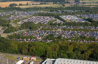 Oblique aerial view through plane window of cars in crowded car parks