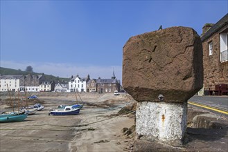 Old stone with sundial and sailing boats at low tide in the picturesque harbour of Stonehaven