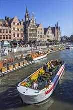 Sightseeing boat with tourists on the river Lys with view over guildhalls at the Graslei