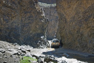 White Land Cruiser driving through narrow rock gorge near Yolun Am in the Gobi Desert