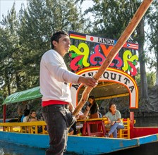 Popular tourist attraction people boating on colourful barges on canal at Xochimiloco