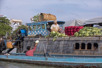 Vietnamese farmer selling vegetables from traditional wooden boat at the floating market of the city Can Tho in the Mekong Delta