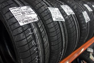 Row of new summer tires on shelf stored in tire centre