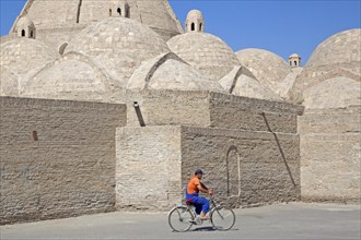 Uzbek man cycling in front of mosque in the ancient historic city of Bukhara