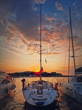 Sunset scene at the harbor as seen through the yachts moored at the deck in the ancient town of Nessebar