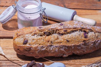 Loaf of rustic raisin bread on a wooden table with flour