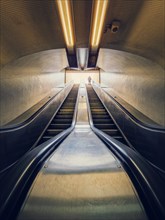 Lone man climbing out on a subway escalator. Symmetrical underground moving staircase