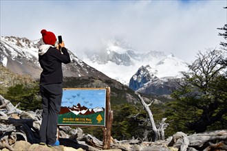 A tourist takes photos with her mobile phone at the Fitz Roy viewpoint in Los Glaciares National Park