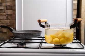 Boiling potato in transparent glass pot on a gas stove