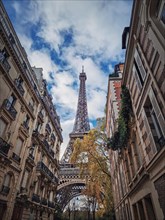 Eiffel tower as seen through the parisian buildings. Snenery autumn season in Paris