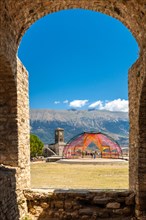 Arches of the fortress of the Ottoman castle of Gjirokaster or Gjirokastra and in the background the church with the clock tower. Albania