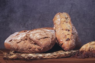 Loaf and loaves of rustic bread with ears of wheat on wooden table
