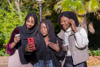 African young women and a Muslim friend taking a selfie in a park