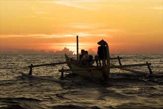 Small boat with outrigger in the sunrise