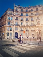 Lone man riding a bicycle near a crosswalk on the Paris city street in the morning