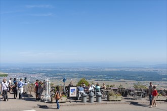 Tourists at the viewpoint in front of the Chateau du Haut Koenigsbourg. In the background the Upper Rhine Plain and the hilly landscape of the Black Forest