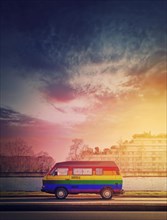 Rainbow painted vintage van parked on the edge of the street in the sunset light background. Lgbtq colors