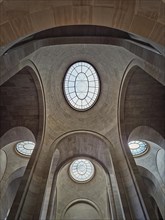 Ceiling architectural details with tall arches and round windows inside Louvre museum hall