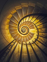 Spiral staircase abstract perspective with view downstairs to infinity swirl stairs in glowing yellow light