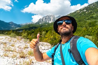 Selfie of a happy man walking in the Valbona valley next to trees