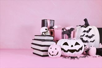 Modern pink Halloween decor with pink and black and white pumpkins and copy space