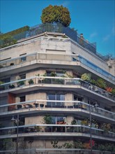 Green eco friendly building with different plants and trees growing on the balconies and on top of the roof in Paris