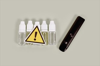 Bottles with liquid solutions and electronic cigarettes with warning sign